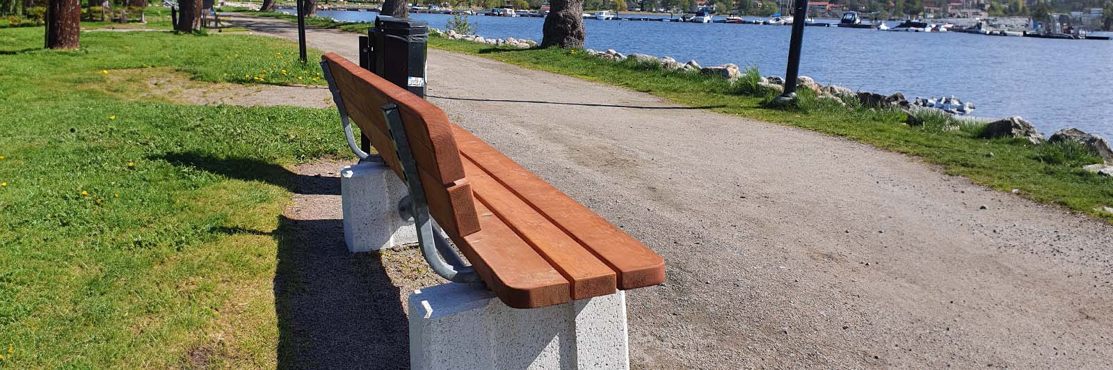 Image of a park bench on a walkway next to a lake.